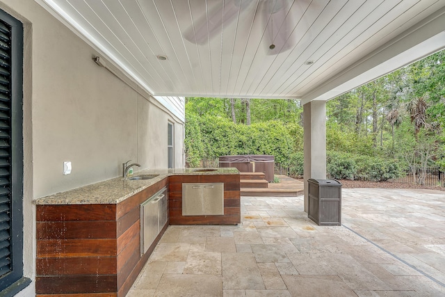 view of patio featuring a sink, fence, area for grilling, and a hot tub