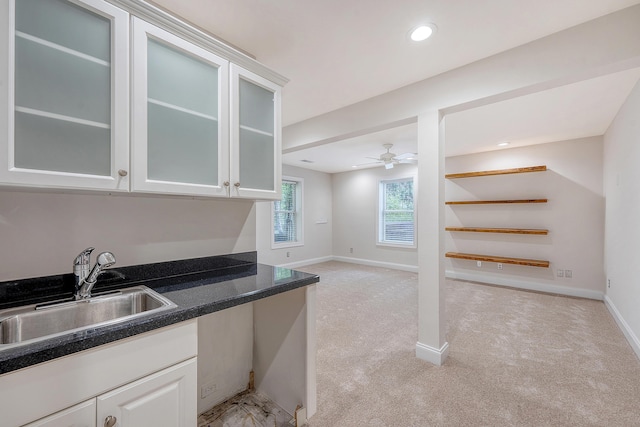 kitchen with light carpet, baseboards, a sink, and a ceiling fan