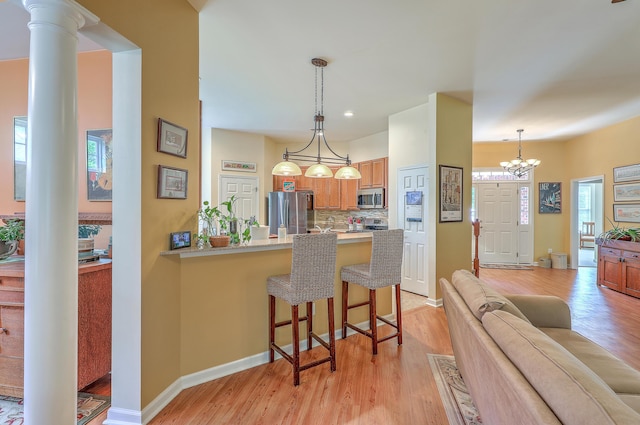 405 Decatur Dr, Summerville, SC 29486 - kitchen with a peninsula, a breakfast bar area, tasteful backsplash, light wood finished floors, and stainless steel appliances