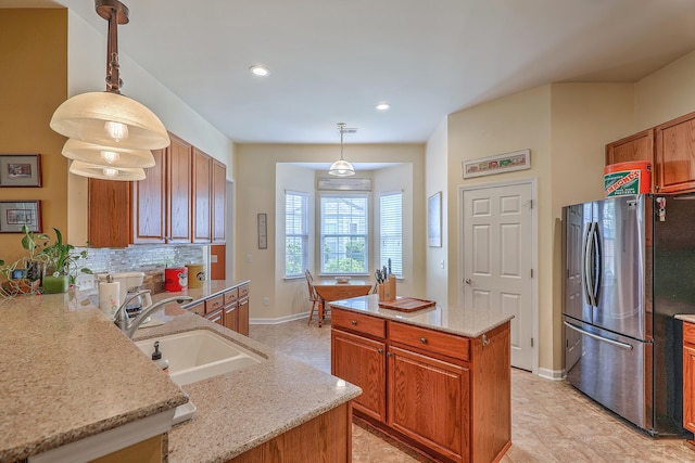 405 Decatur Dr, Summerville, SC 29486 - kitchen with light stone counters, a sink, brown cabinetry, freestanding refrigerator, and baseboards