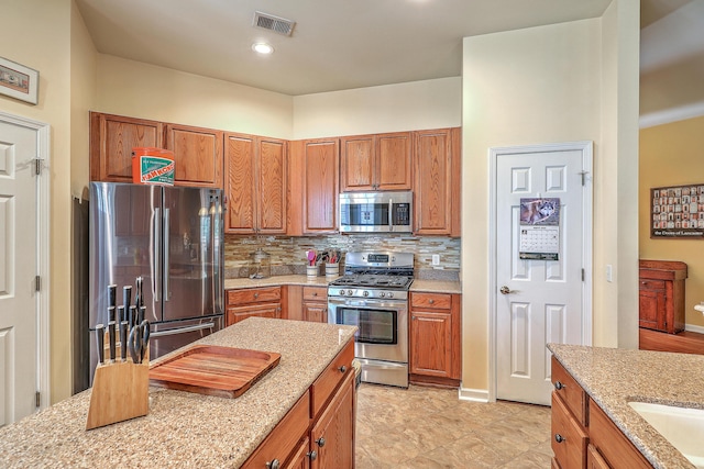 405 Decatur Dr, Summerville, SC 29486 - kitchen with light stone counters, brown cabinetry, stainless steel appliances, tasteful backsplash, and visible vents