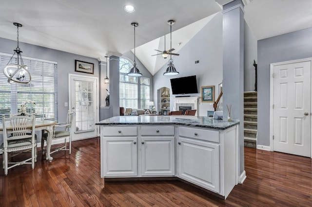 kitchen with dark wood finished floors, a fireplace, open floor plan, white cabinetry, and dark stone countertops