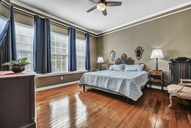 bedroom with ornamental molding, wood-type flooring, baseboards, and a ceiling fan