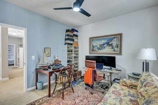 carpeted office space with ceiling fan and baseboards