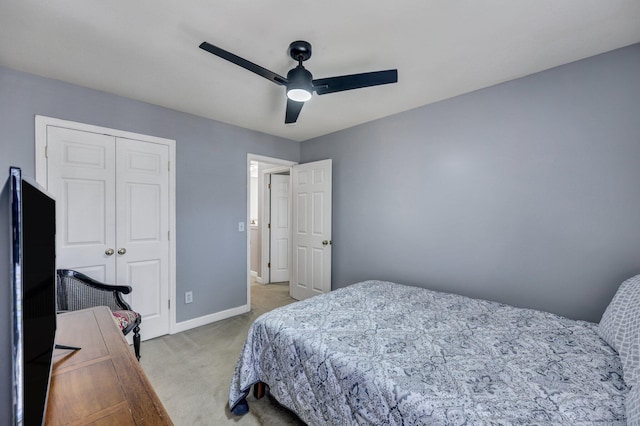 bedroom featuring a ceiling fan, a closet, light carpet, and baseboards