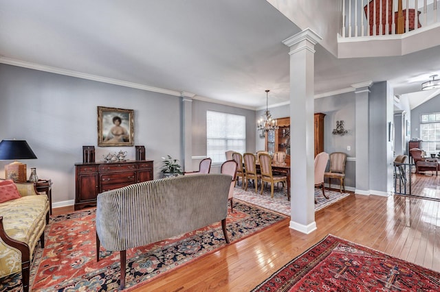 living room featuring crown molding, baseboards, decorative columns, and hardwood / wood-style floors