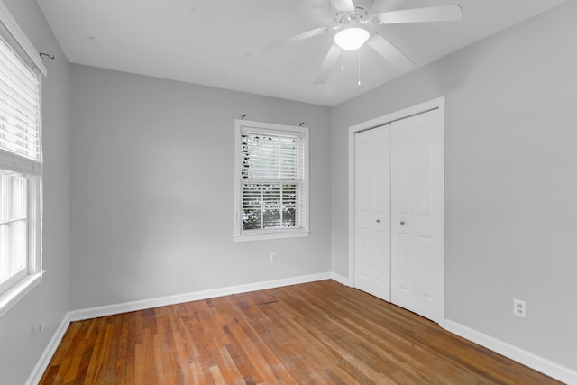 unfurnished bedroom featuring a closet, baseboards, a ceiling fan, and wood finished floors