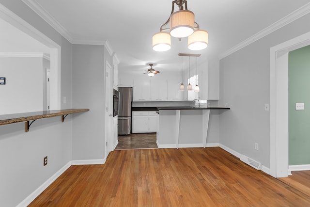 kitchen with ceiling fan, freestanding refrigerator, a peninsula, white cabinets, and dark countertops