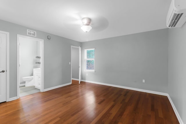 unfurnished bedroom featuring a wall mounted AC, wood finished floors, baseboards, and visible vents