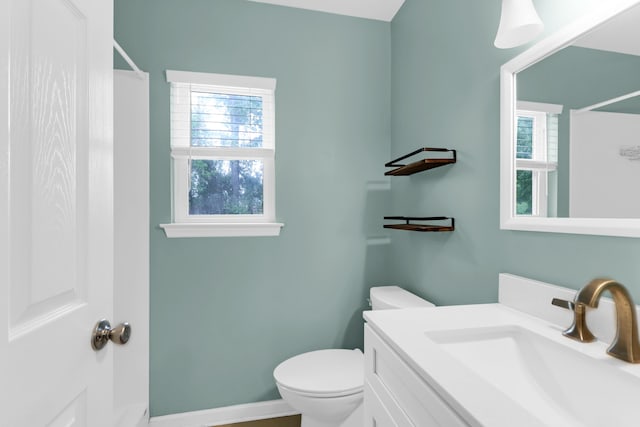 bathroom featuring toilet, walk in shower, vanity, and a healthy amount of sunlight