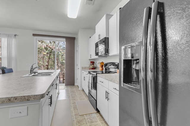 kitchen with sink, electric range oven, fridge with ice dispenser, white cabinets, and a center island with sink