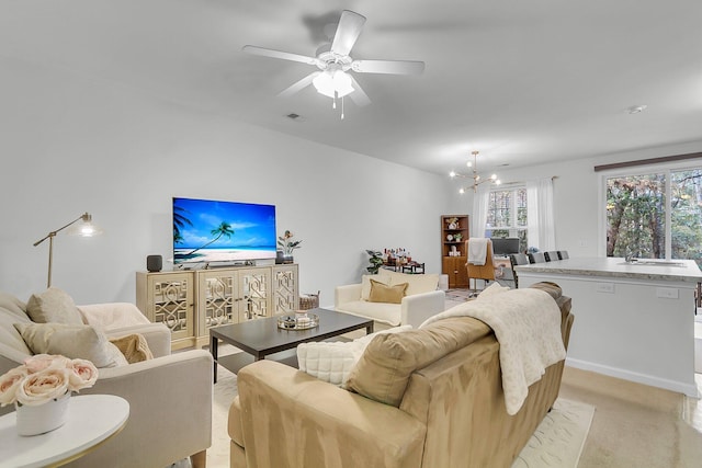 living room featuring sink and ceiling fan with notable chandelier