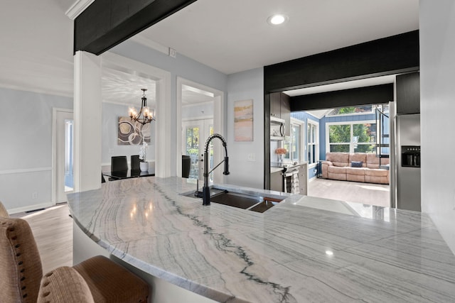 kitchen with light hardwood / wood-style floors, sink, kitchen peninsula, a notable chandelier, and pendant lighting