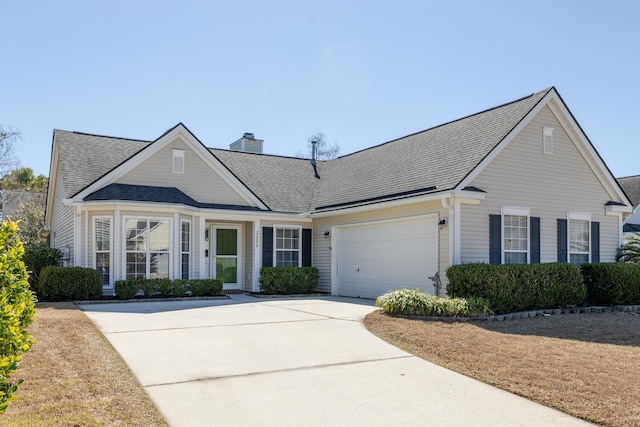 traditional home with a garage, driveway, a shingled roof, and a chimney