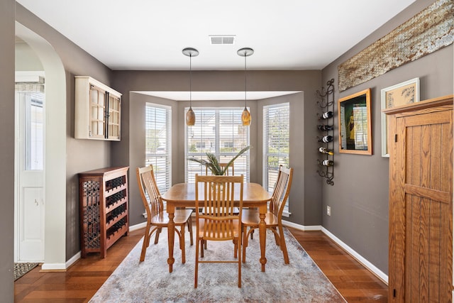 dining area with baseboards, arched walkways, and wood finished floors