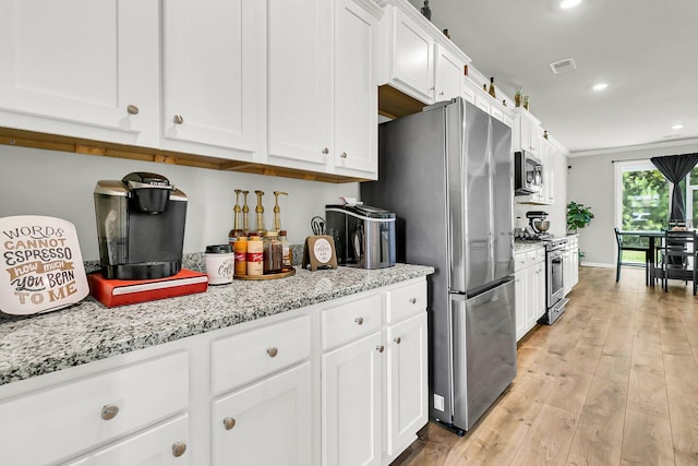 kitchen with white cabinetry, appliances with stainless steel finishes, light stone countertops, and light hardwood / wood-style flooring