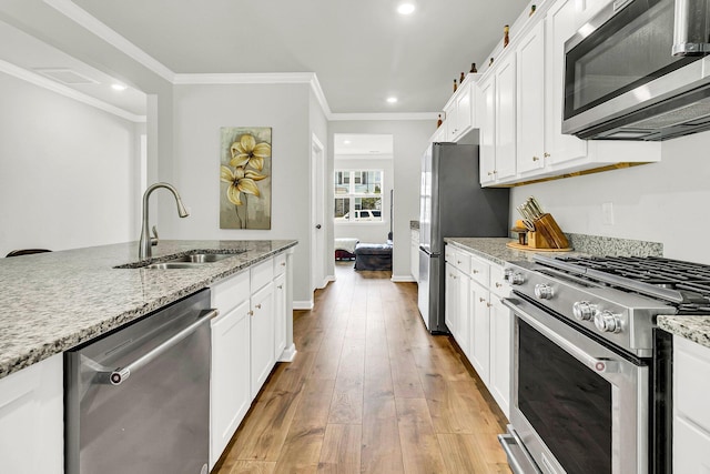 kitchen with light hardwood / wood-style flooring, stainless steel appliances, light stone countertops, white cabinets, and sink