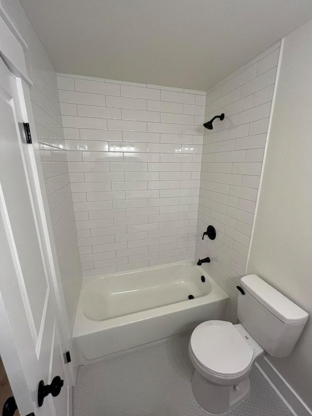 bathroom with tile patterned flooring, toilet, and tiled shower / bath combo