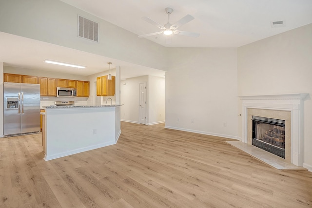 kitchen featuring stainless steel appliances, visible vents, open floor plan, brown cabinetry, and pendant lighting