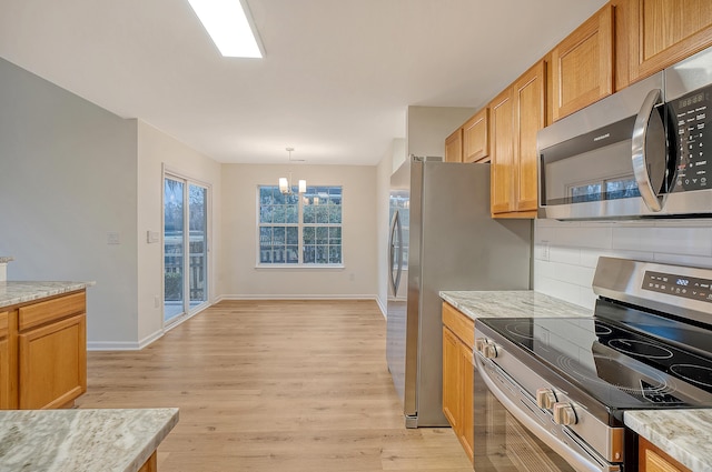 kitchen featuring stainless steel appliances, light wood-type flooring, light stone counters, and tasteful backsplash