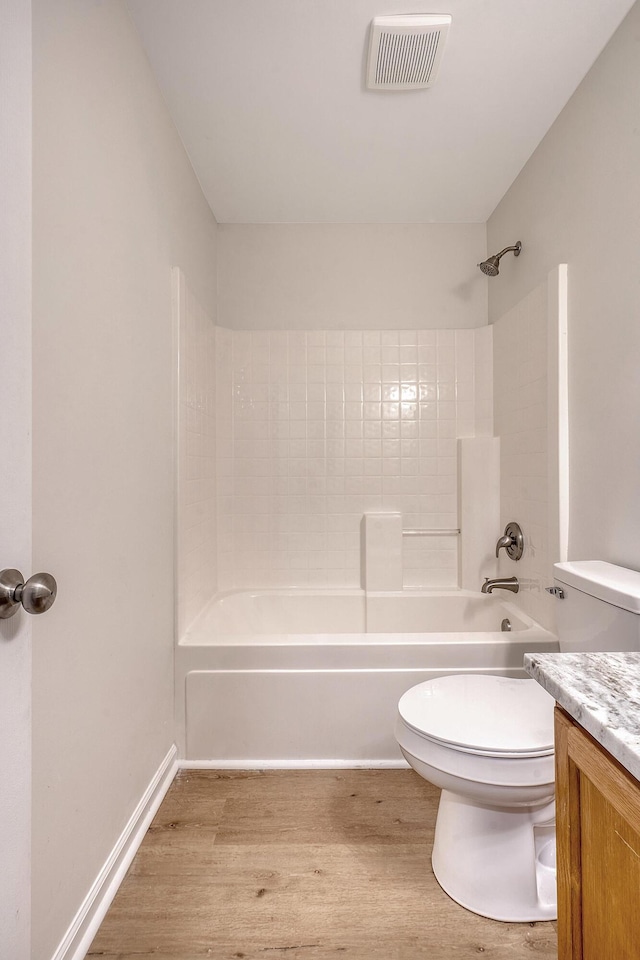 bathroom with toilet, wood finished floors, vanity, visible vents, and  shower combination