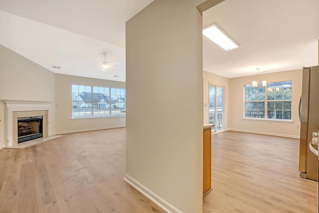 unfurnished living room featuring light wood-style flooring, baseboards, vaulted ceiling, and a high end fireplace