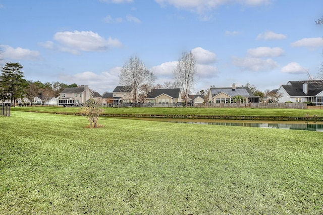 view of yard with a water view, fence, and a residential view