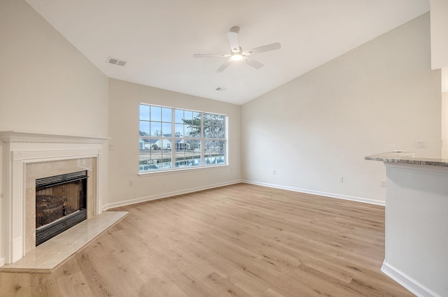 unfurnished living room featuring lofted ceiling, a ceiling fan, a high end fireplace, baseboards, and light wood finished floors