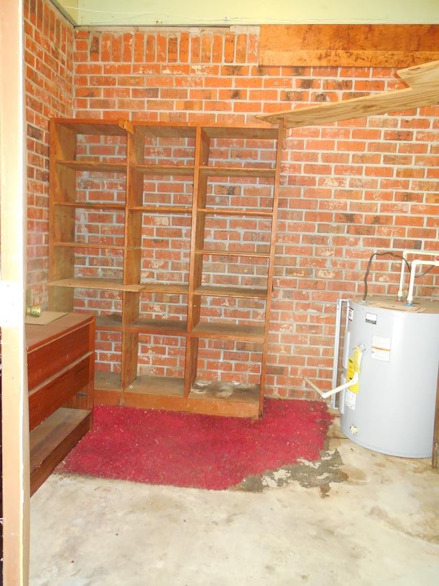 interior space featuring brick wall, water heater, and concrete flooring