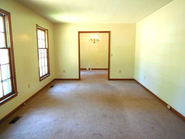 carpeted spare room with an inviting chandelier