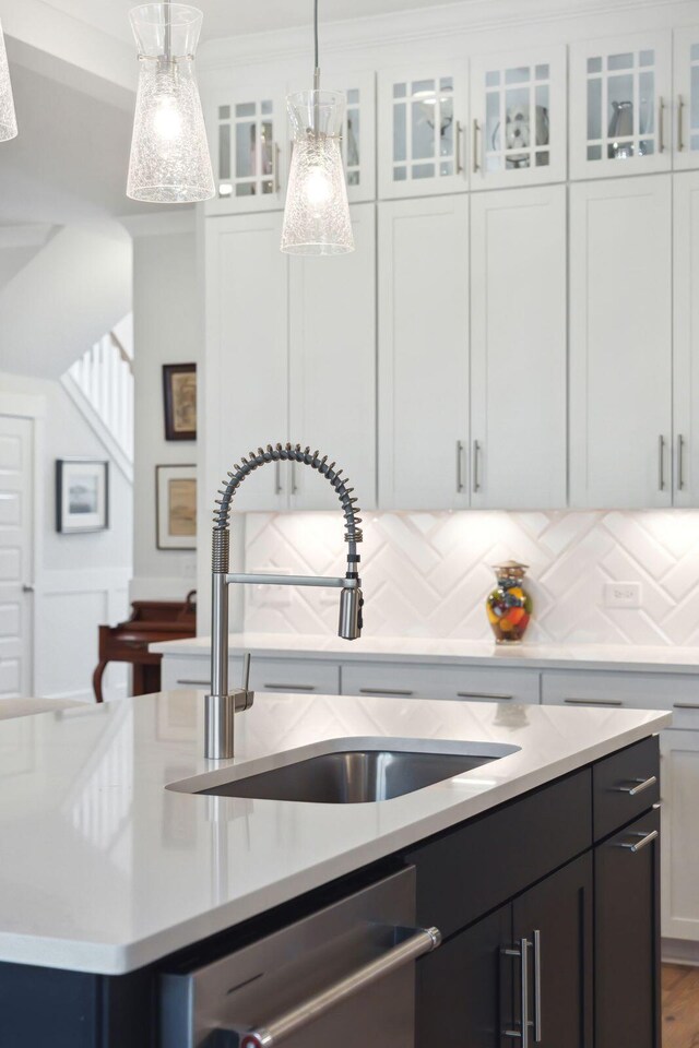 kitchen featuring dishwasher, white cabinetry, sink, and decorative light fixtures