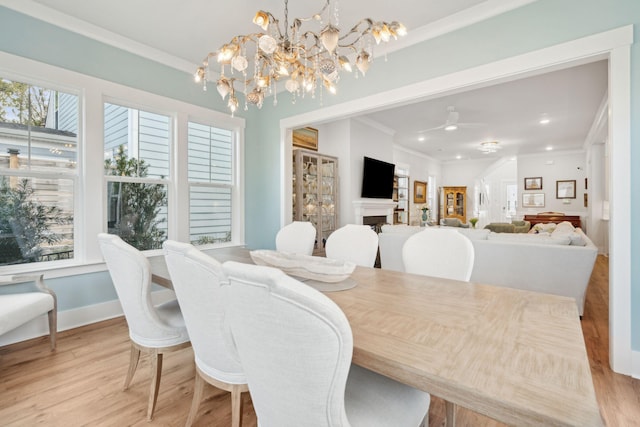 dining space with ornamental molding, ceiling fan with notable chandelier, and light wood-type flooring