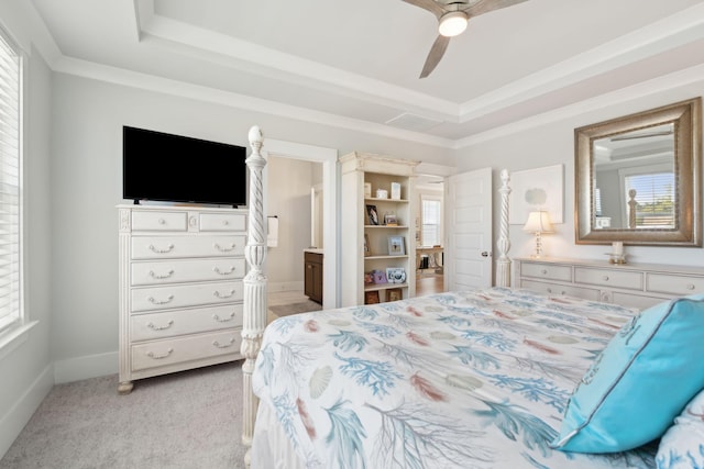 bedroom featuring ceiling fan, ensuite bathroom, ornamental molding, light carpet, and a raised ceiling