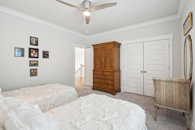 bedroom with ornamental molding, light carpet, ceiling fan, and a closet