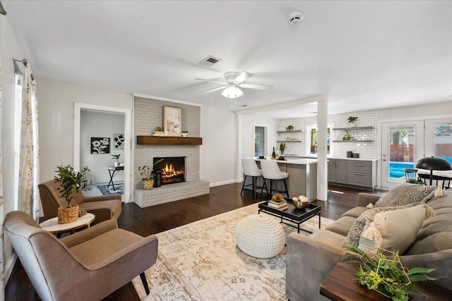 living room with dark wood-type flooring, a fireplace, and ceiling fan