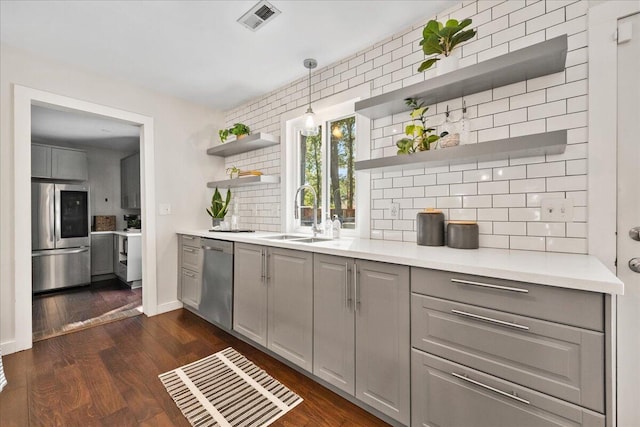 kitchen with appliances with stainless steel finishes, gray cabinetry, sink, and dark hardwood / wood-style flooring