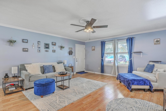living room with baseboards, wood finished floors, ceiling fan, and crown molding