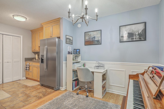 office featuring a textured ceiling, light wood finished floors, a notable chandelier, and wainscoting