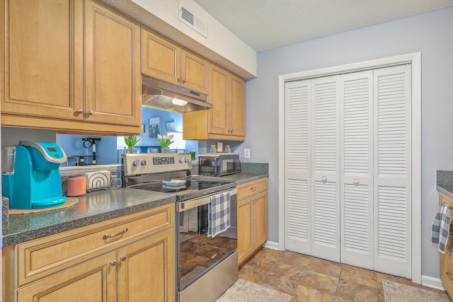 kitchen with stainless steel range with electric cooktop, dark countertops, baseboards, visible vents, and under cabinet range hood