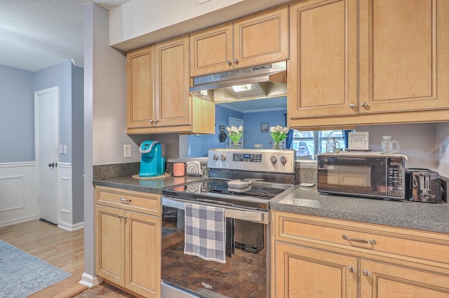 kitchen with dark countertops, stainless steel electric range, black microwave, light wood finished floors, and under cabinet range hood