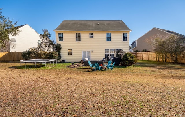 rear view of property featuring a yard and a trampoline