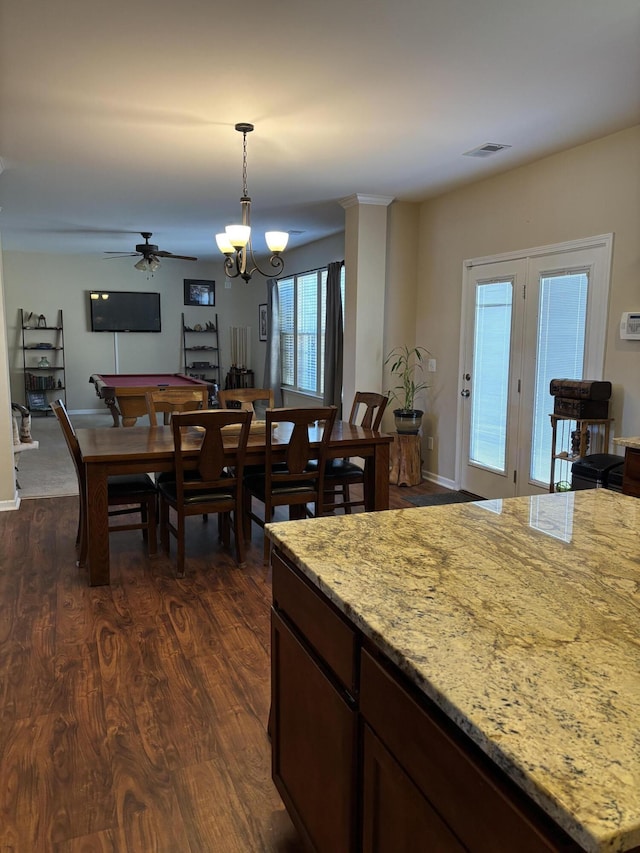 kitchen featuring pendant lighting, dark hardwood / wood-style flooring, light stone counters, and a notable chandelier