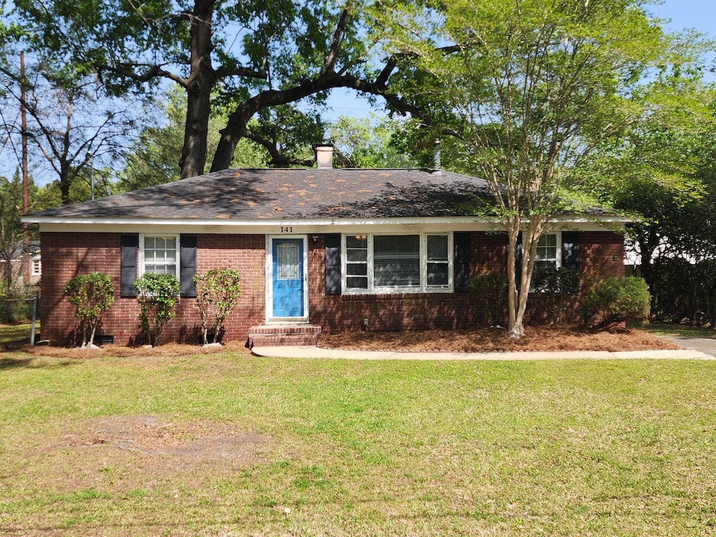 single story home with brick siding, entry steps, roof with shingles, and a front lawn