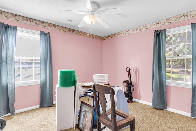 interior space with a textured ceiling, light colored carpet, and ceiling fan