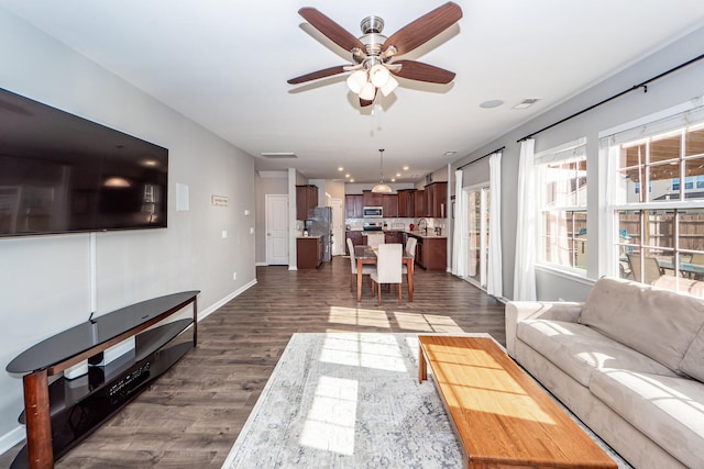 living room featuring dark wood-type flooring and ceiling fan