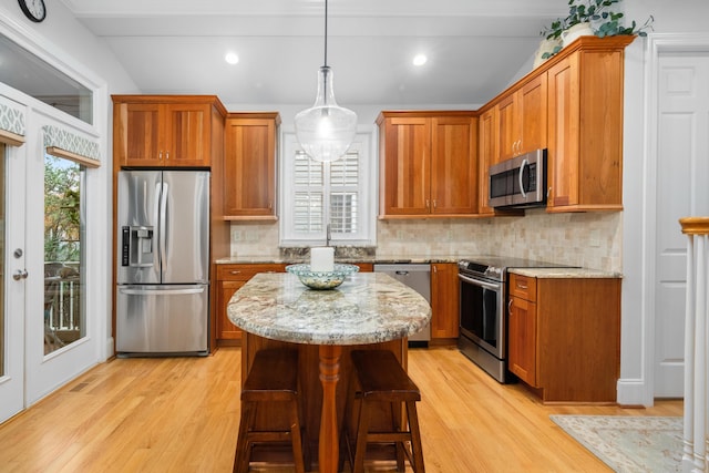 kitchen featuring a kitchen island, light stone counters, light hardwood / wood-style floors, and appliances with stainless steel finishes