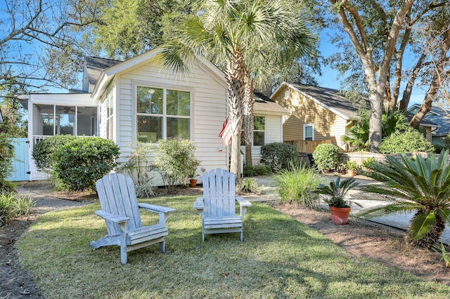 rear view of house featuring a lawn and a sunroom