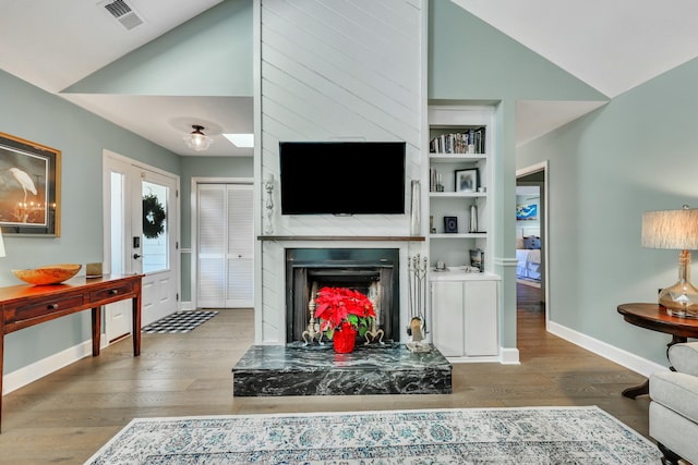 living room featuring built in shelves, lofted ceiling, and hardwood / wood-style flooring