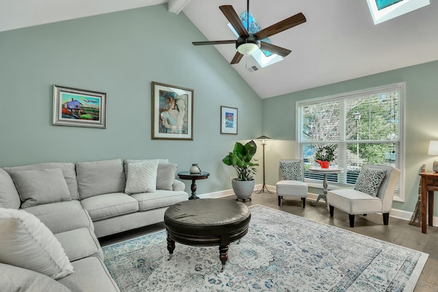 living room featuring hardwood / wood-style floors, high vaulted ceiling, a skylight, ceiling fan, and beam ceiling