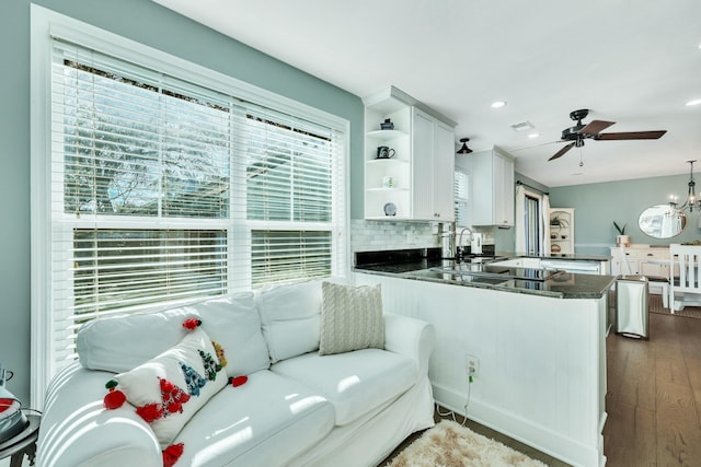 living room featuring ceiling fan, sink, and dark wood-type flooring